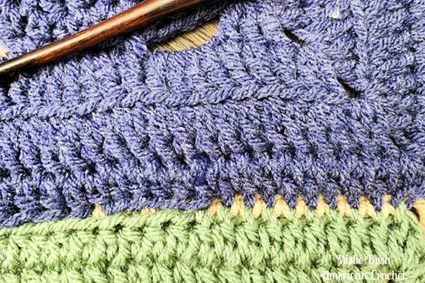 Demonstration of slip stitch seam halfway through joining two crochet squares.