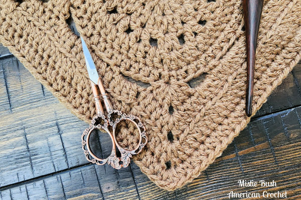 A partially completed Pilot Square on a crochet hook, showing the stitch texture and pattern development.