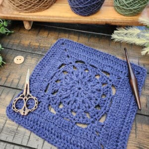 Blessed Square crochet pattern – 9-inch square using treble crochet and back loop only stitches. Styled flat with scissors and wooden crochet hook.