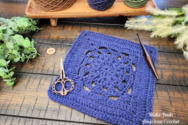 Blessed Square crochet block laid flat on a wooden background, showing stitch height and subtle back loop texture.